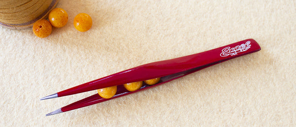 a pair of hollow point tweezers holding several beads