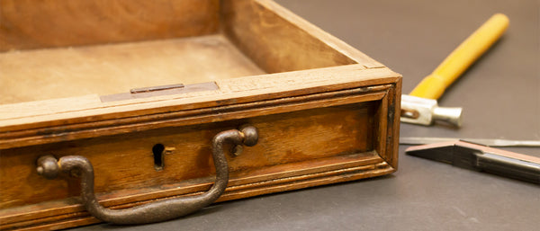 an antique wooden box with a handle