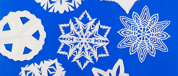 different styles of paper snowflakes against a blue background