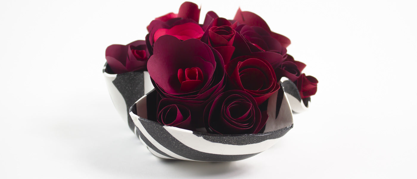 a decorative bowl full of paper roses