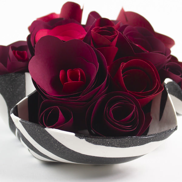 a decorative bowl full of paper roses